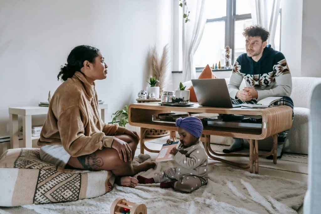 Woman taking care of their child and a man busy working