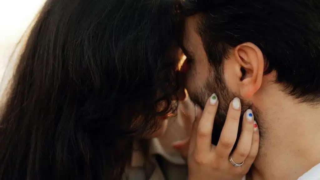 A woman gently holding a man’s face while leaning in close.