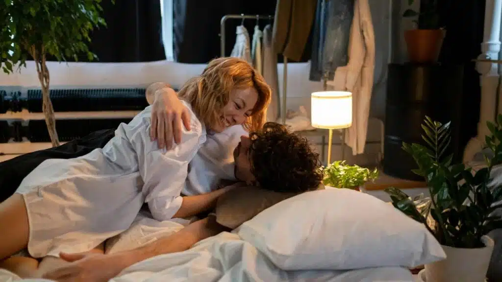 A couple lying on a bed smiling at each other in a cozy room.