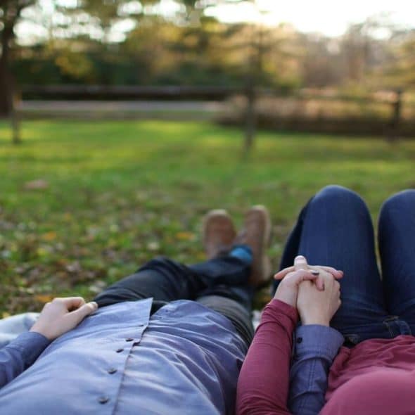 A couple holding hands while laying on the grass