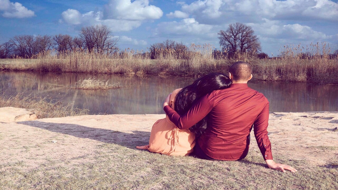 A couple hugging while looking at a body of water
