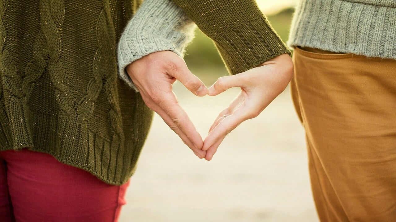 A couple forming a heart shape with their hands