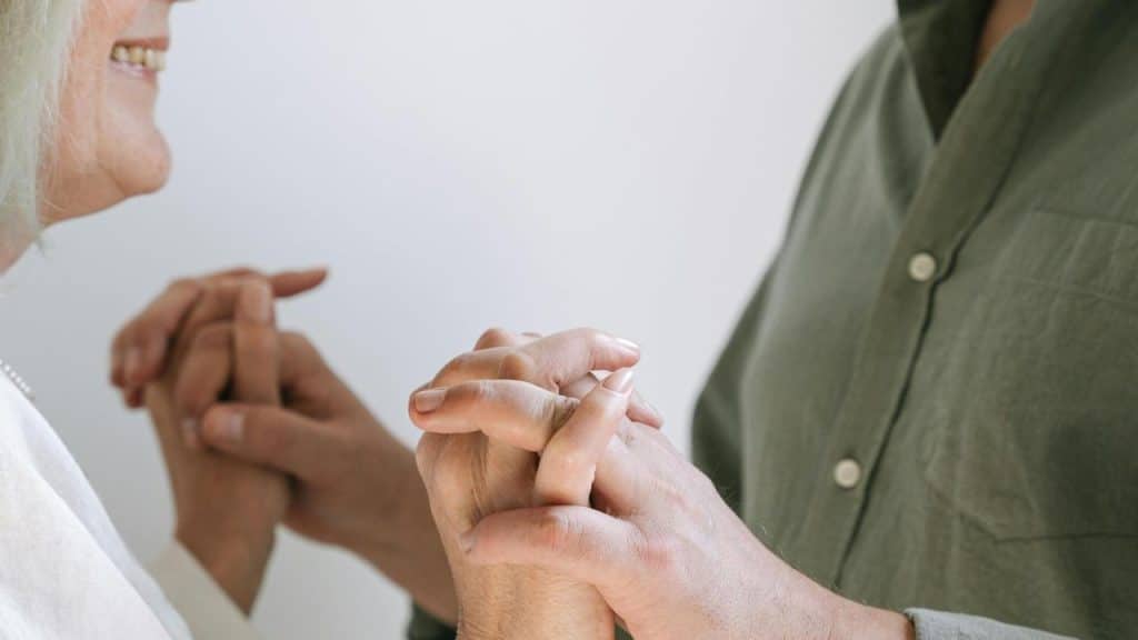 An older couple holding hands and smiling while standing together.