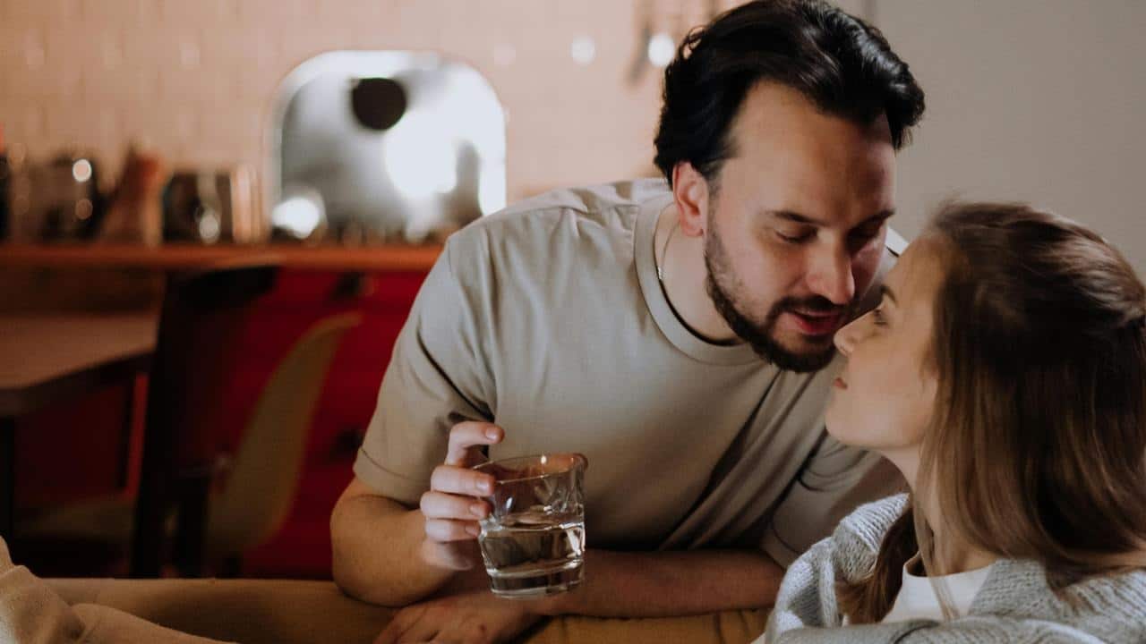A couple sitting close together on a couch, sharing an intimate moment indoors.