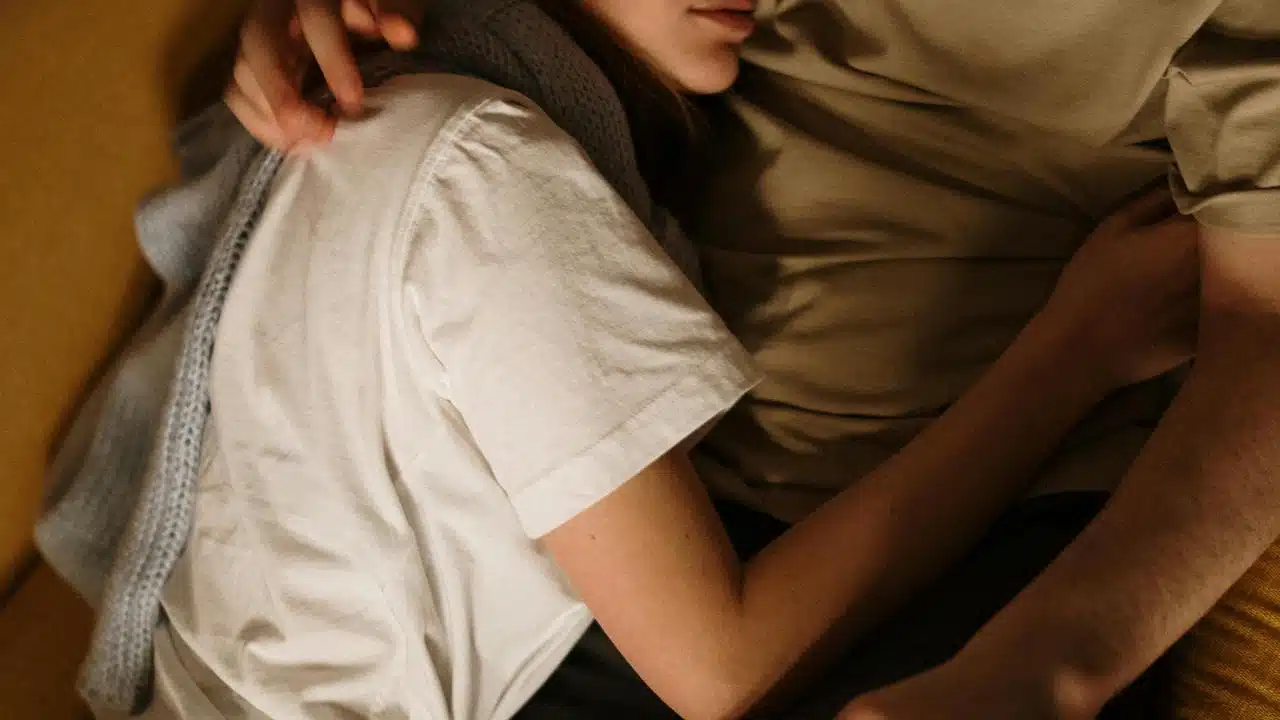 A couple cuddling closely on a couch, showing a warm and intimate moment.