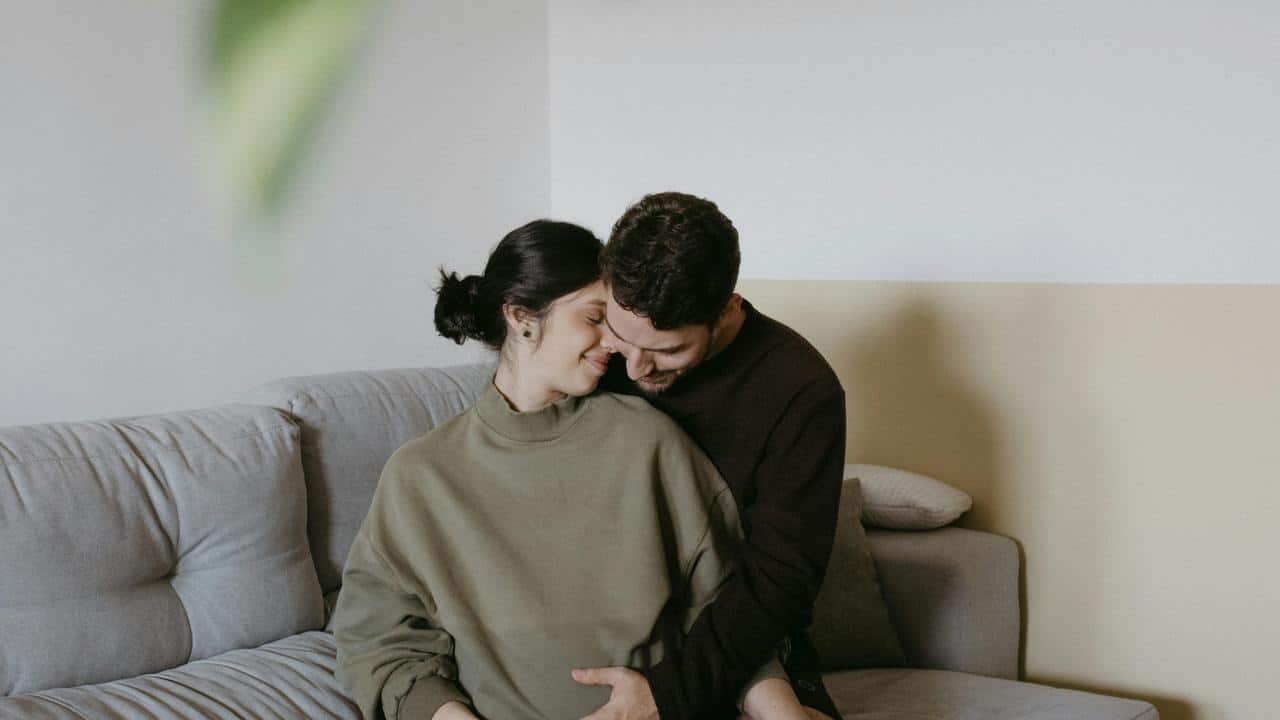 A couple sitting on a couch, sharing an intimate and tender moment.