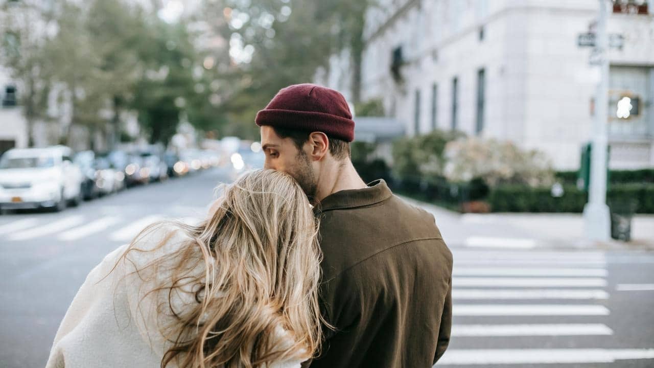 A couple standing close together on a city street.