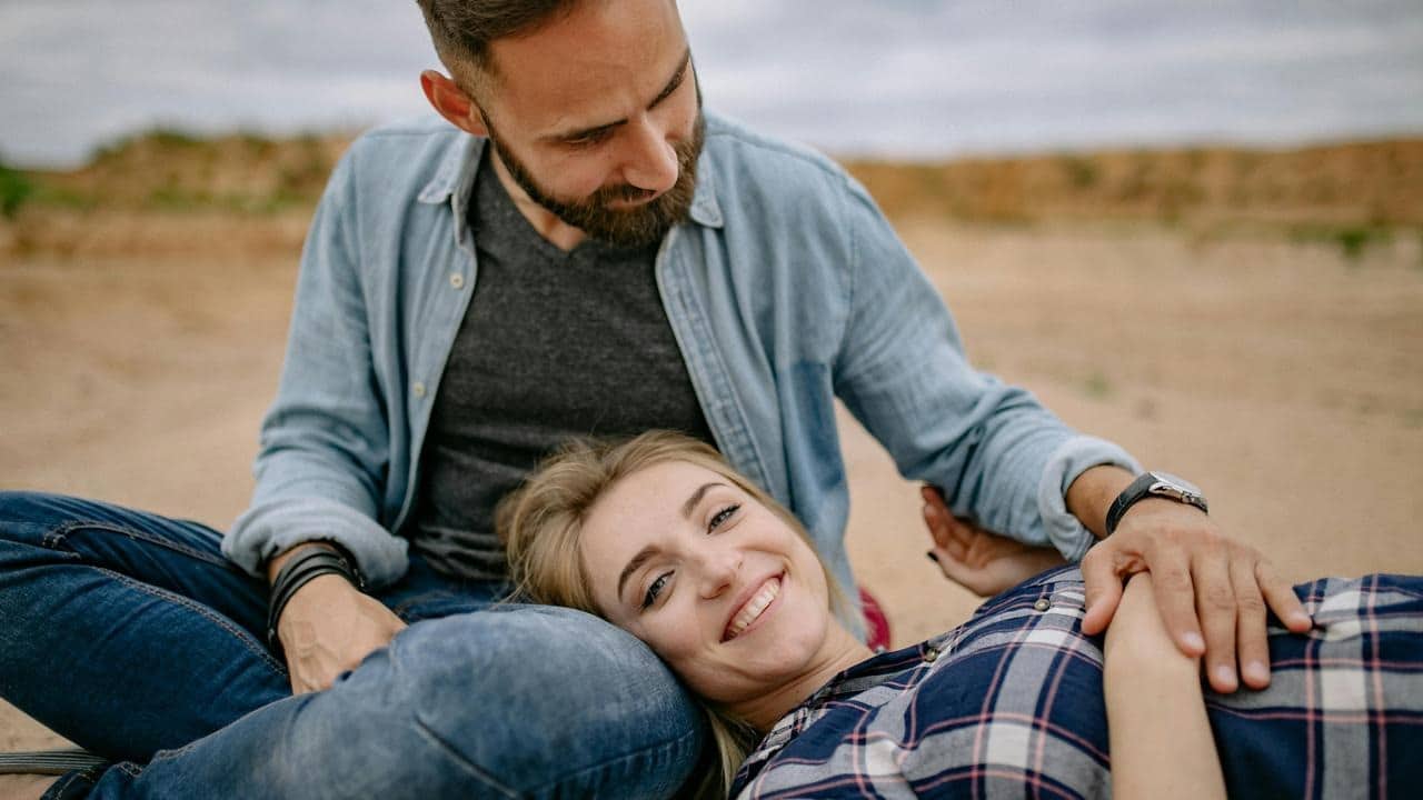 A couple relaxing together outdoors, with one resting their head on the other's lap.