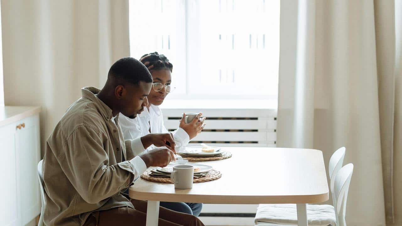 A couple eating breakfast together at a small kitchen table.