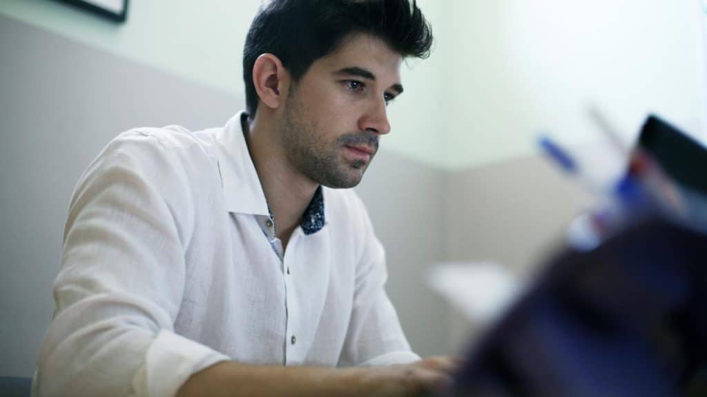 A focused man working at a desk indoors.