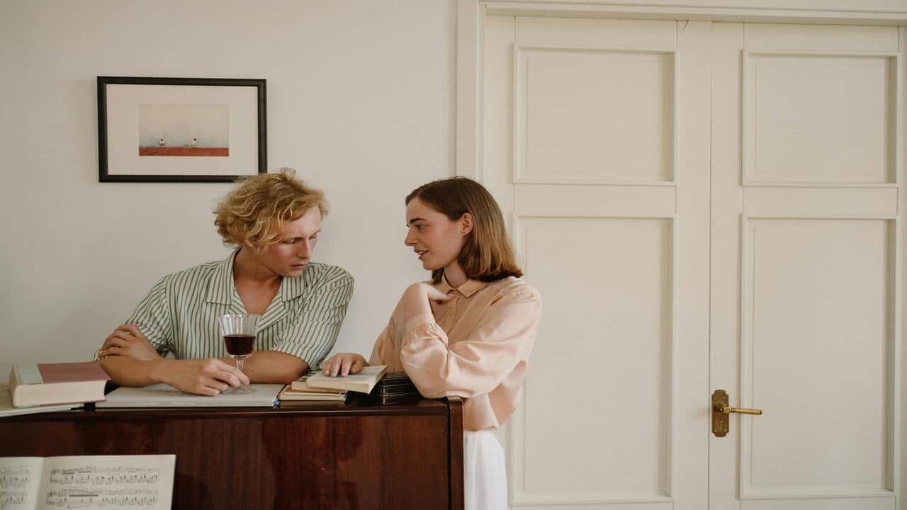 A couple talking by the piano