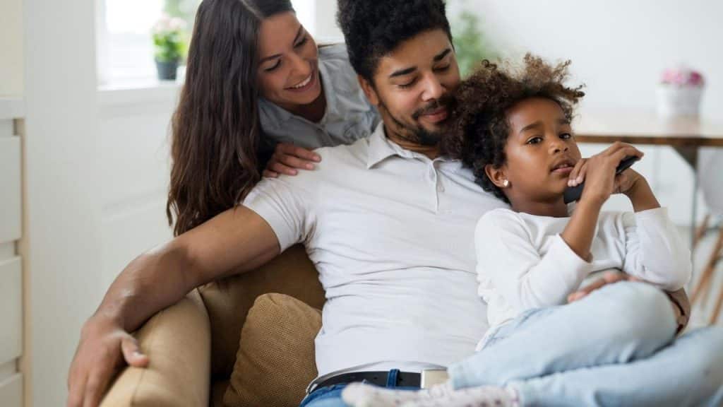 A relaxed family sitting together on a couch at home.