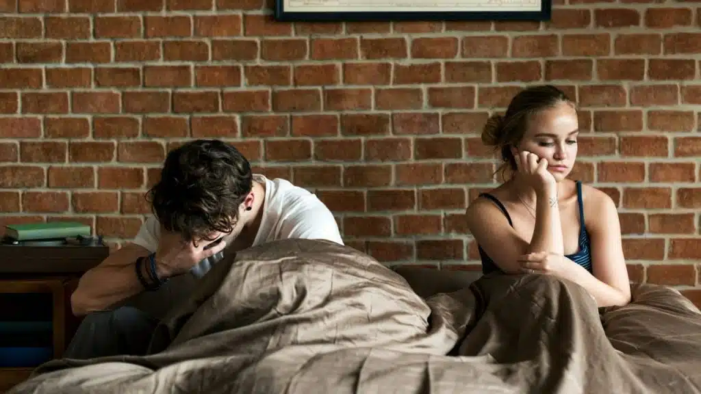 A man sits with his head in his hands while a woman sits facing away.