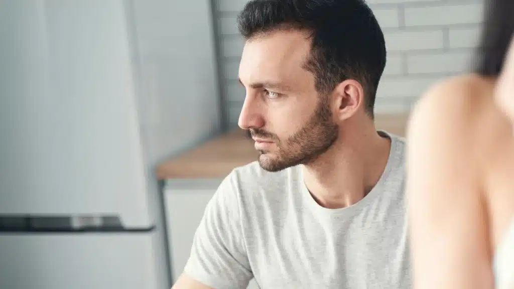 Close-up profile of a man with dark hair looking away with a neutral, steady facial expression.