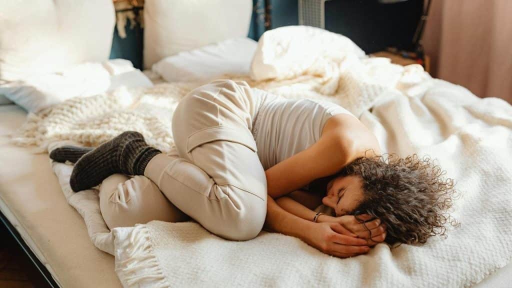 A woman curled up on a bed