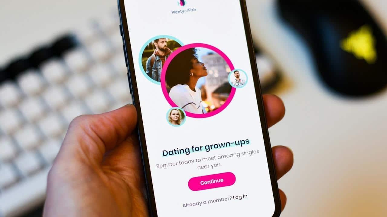 A person holding a phone with a dating app with multiple profile pictures on the smartphone screen.