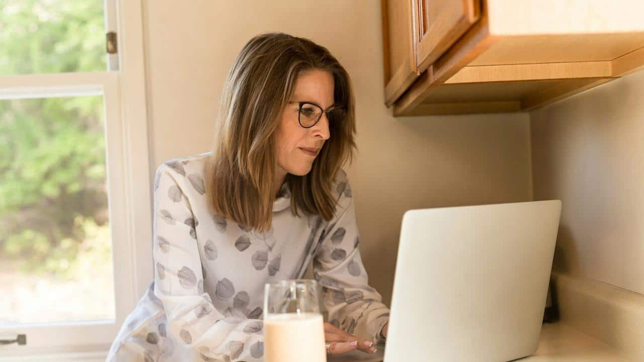 A bespectacled mature woman using a laptop.