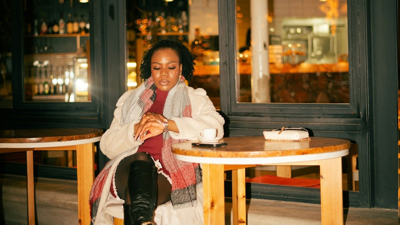 A woman sitting at a table while looking at her wristwatch.