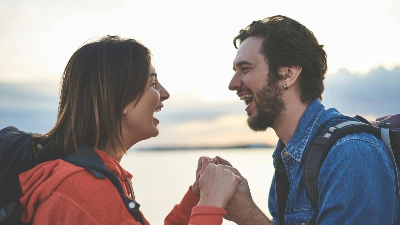 A couple laughing and holding hands outdoors.