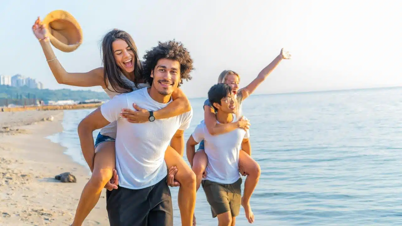 A group of friends enjoying piggyback rides on the beach.