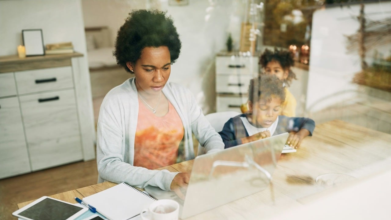 A woman working on her laptop while her kids play.