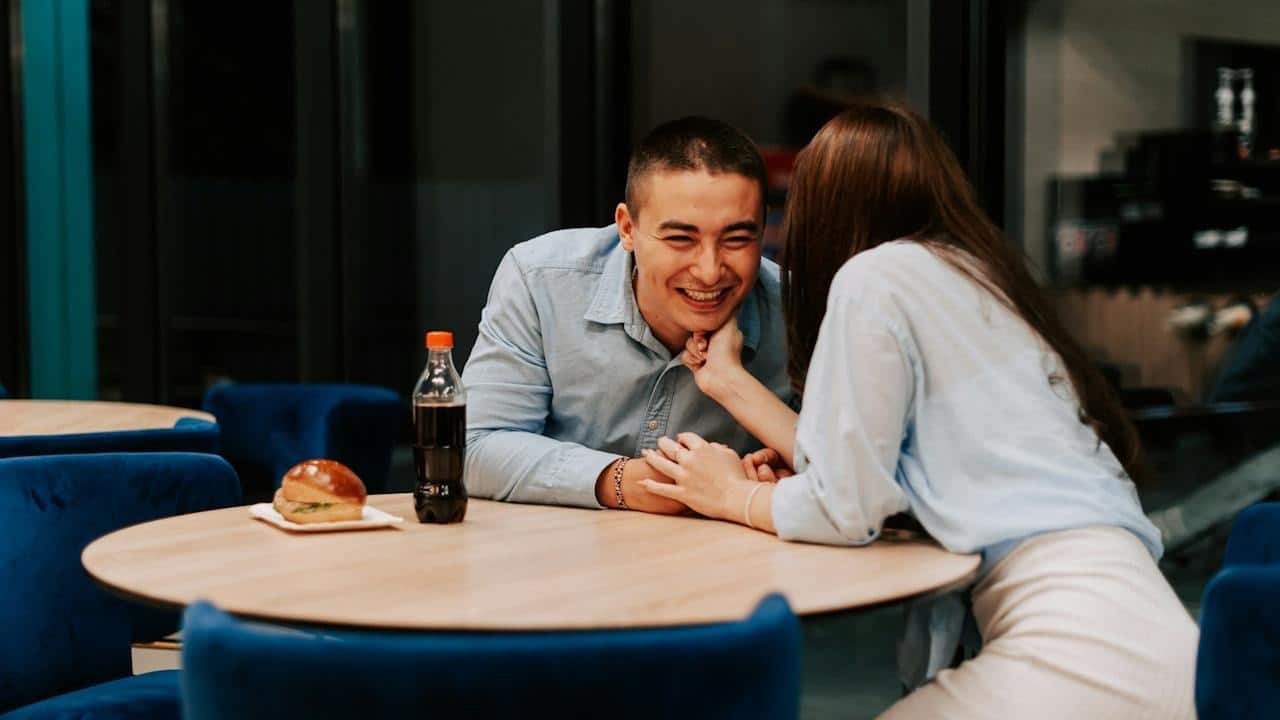 A woman whispering something in a man’s ear.