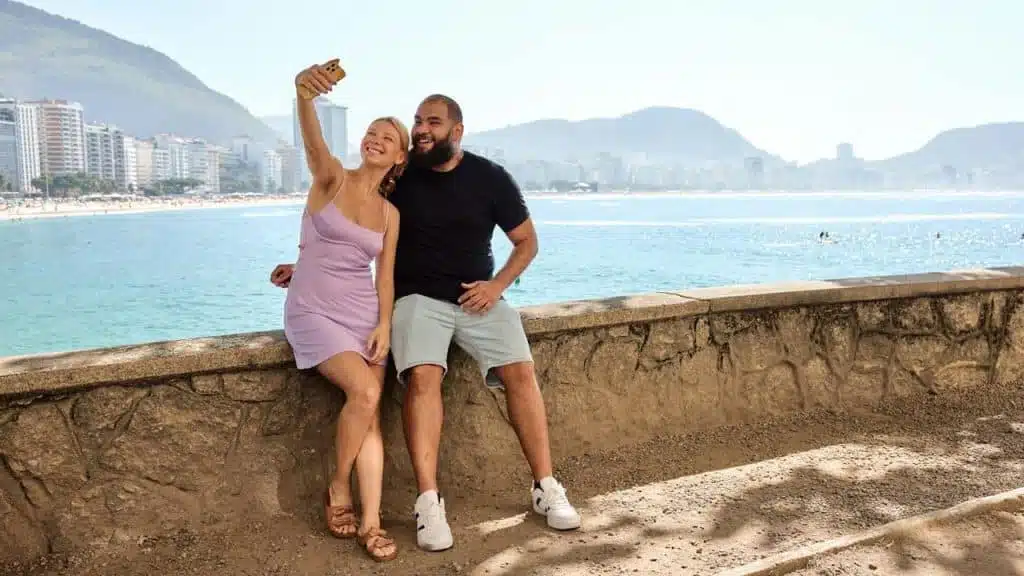 A man and a woman pose for a picture by the water.