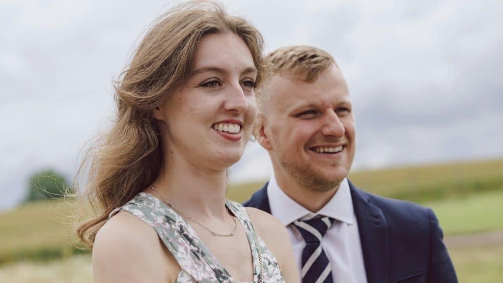A smiling man and a woman standing in a field.