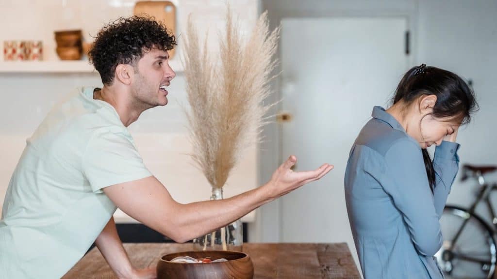 A man is aggressively yelling and gesturing at a woman who is turned away from him.