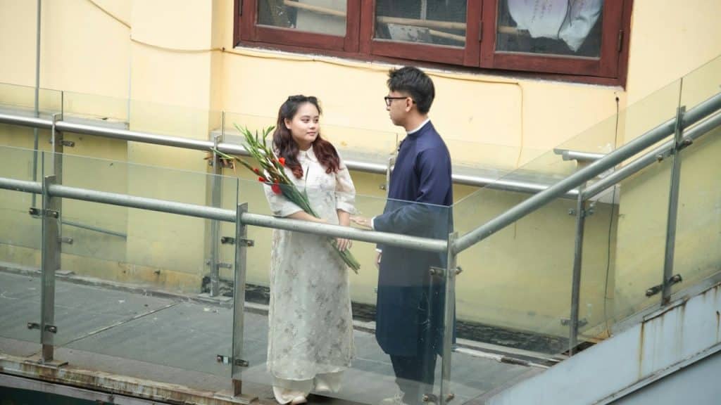 A man giving a flower bouquet to a woman standing next to him.