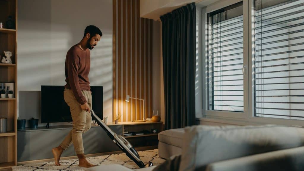 A man vacuuming his room.