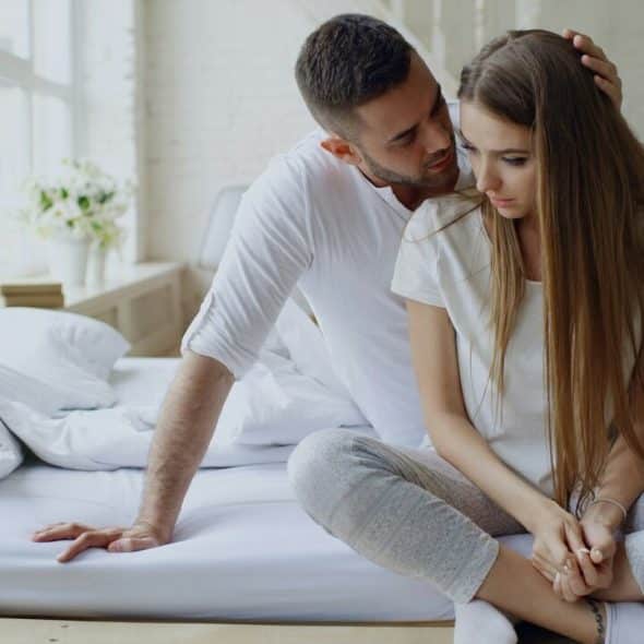 A man whispering to his wife in bed