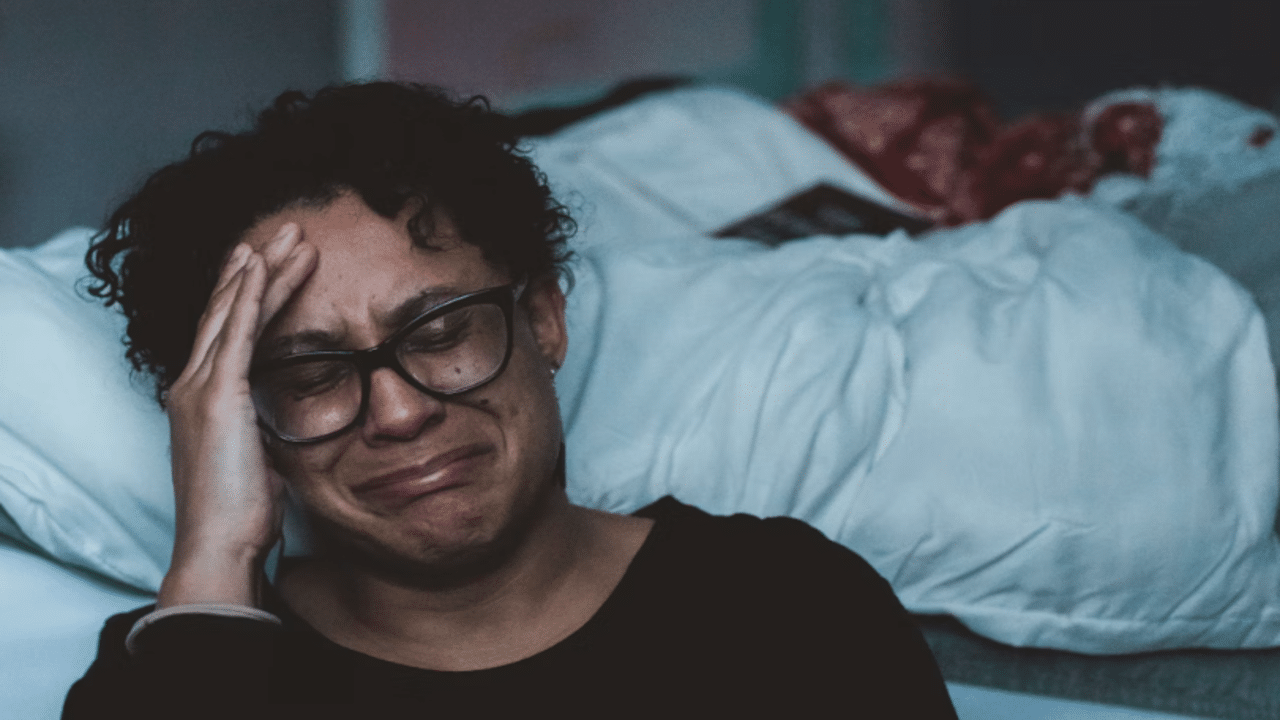 A woman crying beside her bed
