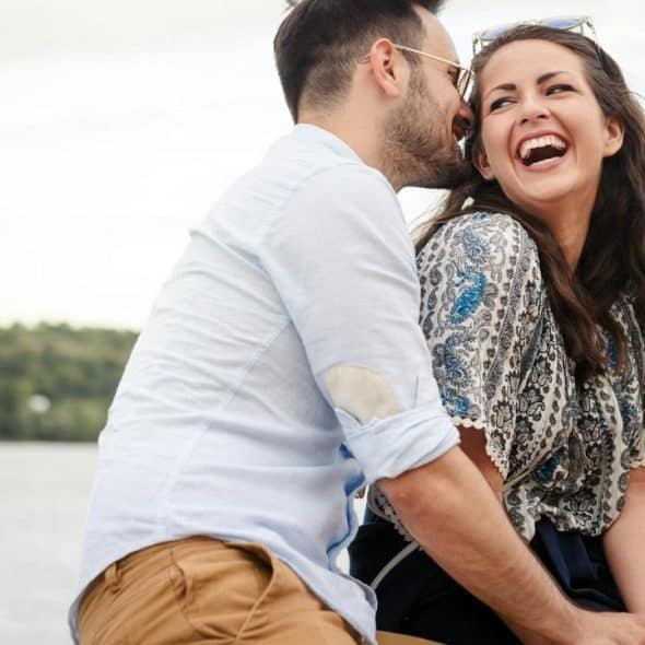 A man whispering to a laughing woman