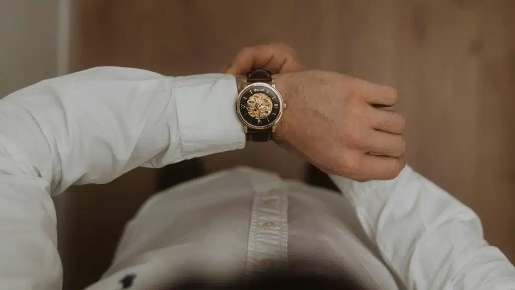 A first-person view of a person lying down wearing a white shirt and a gold watch.