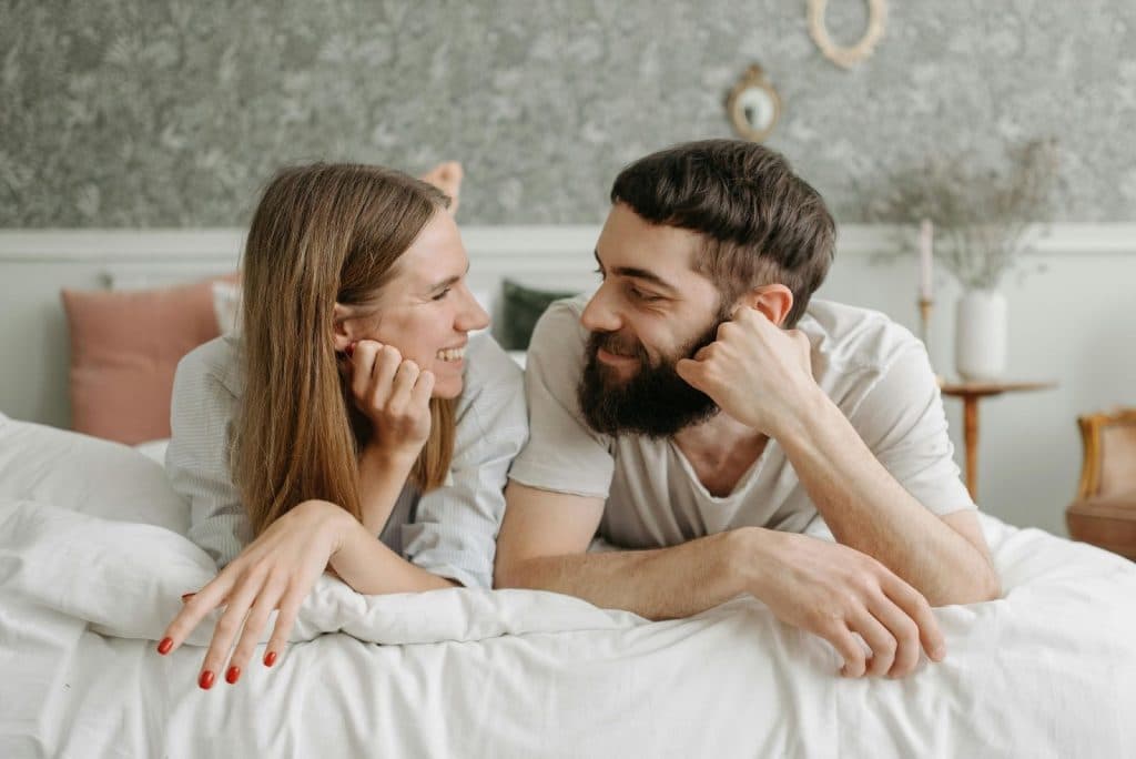 A man and woman at the bed while looking at each	other