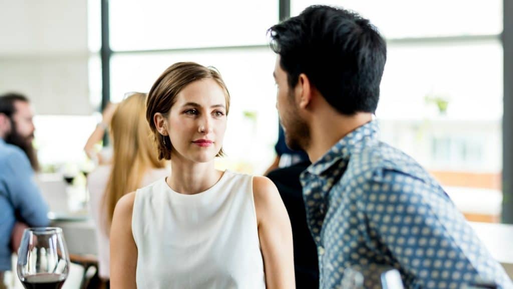 A couple looking at each other while sitting at a table.