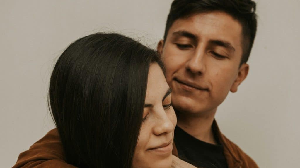 A man hugging a woman from the backside.