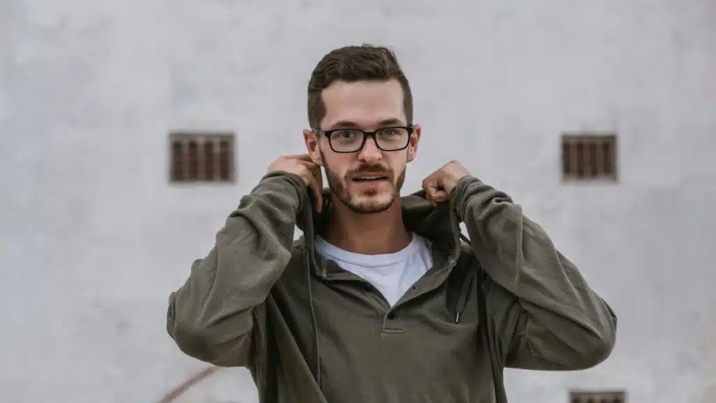 A man wearing glasses and a hoodie posing for the camera.