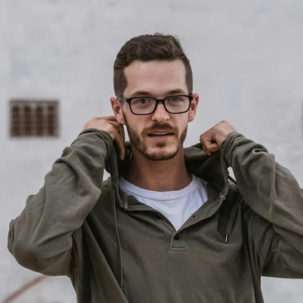 A man wearing glasses and a hoodie posing for the camera.