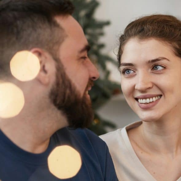 A couple looking at each other while sitting close to each other.