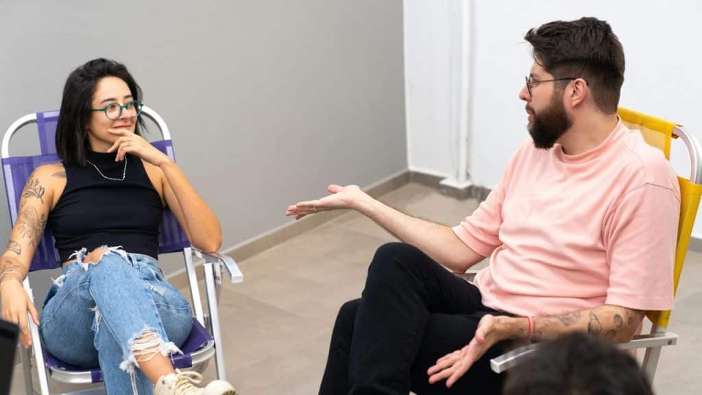 A couple discussing something while siting on a chairs together.