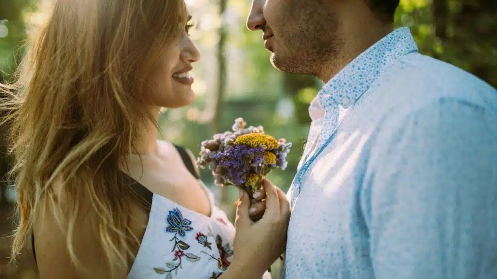 A man giving flowers to a woman standing next to him.