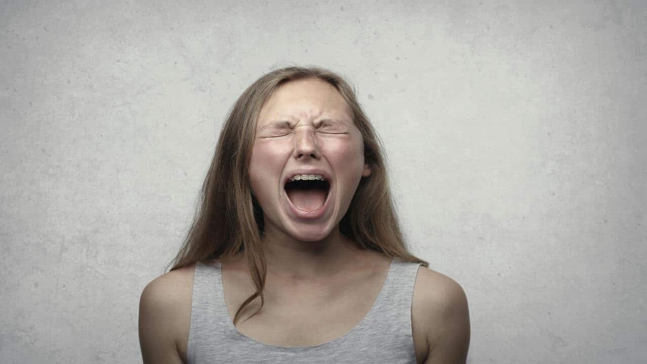 A woman in grey tank top yelling