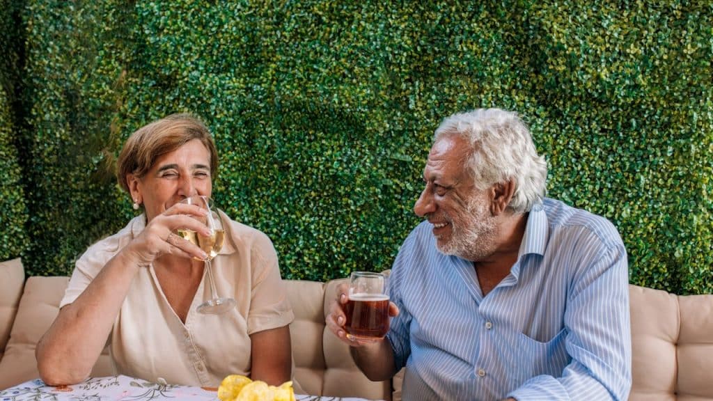 A mature couple enjoying drinks and snacks together.
