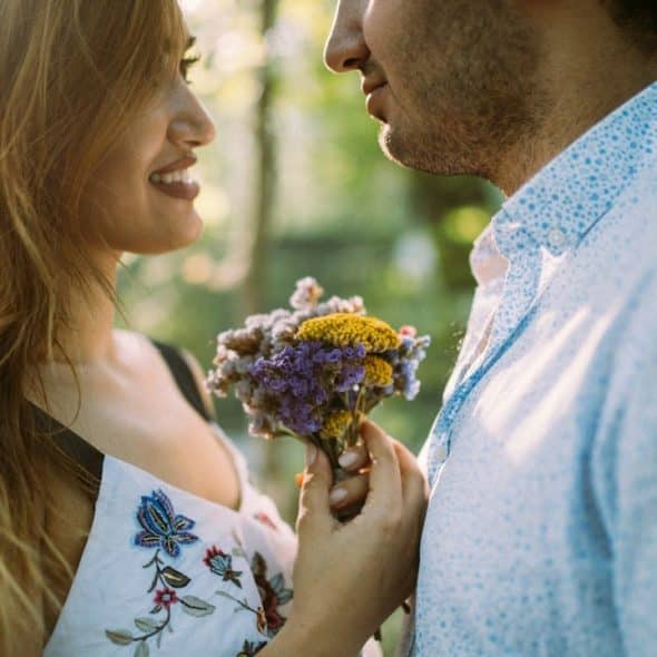 A man giving flowers to a woman standing next to him.
