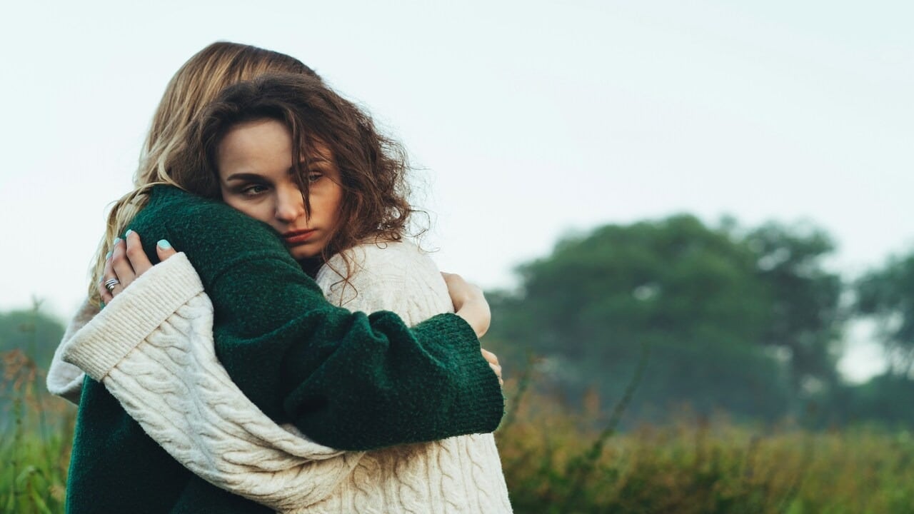 Two women hugging in a field