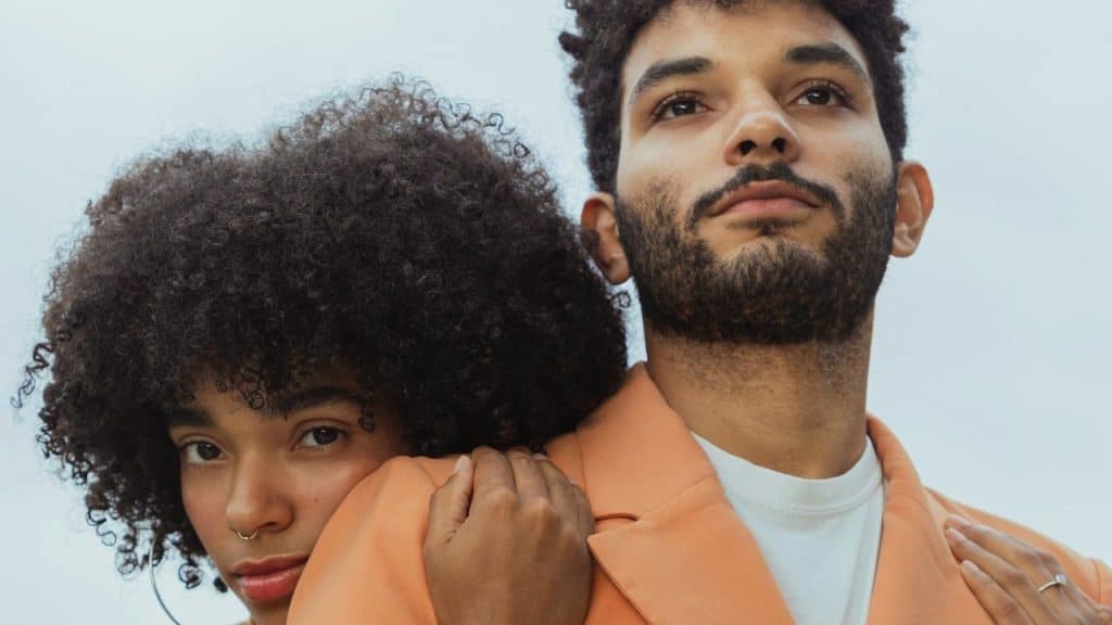 A woman with curly hair hugging a man from the backside.