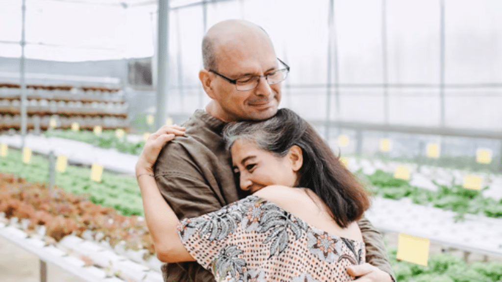 A mature couple hugging in a green house 