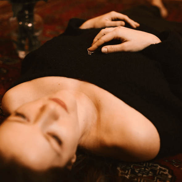 Sad Woman Lying on the Floor with a Ring on her Chest